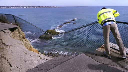 Public Services Director Bill Riccio peers down at debris along the historic Cliff Walk, Tuesday, March 15, 2022, in Newport, R.I. A roughly 30-foot section of the walk crumbled into the sea last week, leaving officials to ponder whether to rebuild or let if continue to fall into the ocean. (AP Photo/Charles Krupa)