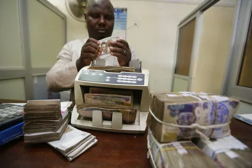 A money changer counts Nigerian naira currency at a bureau de change, in Lagos Nigeria, Oct. 20, 2015. Nigeria's push to replace the local currency notes with newly designed ones is creating an economic crisis, experts warned Monday, Jan. 30, 2023 with the limited cash in circulation hurting many people and businesses across the West African nation. (AP Photo/Sunday Alamba, File)