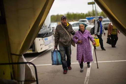 Kateryna Hodza, 85, and her grandson Artem Dorschenko arrive at a reception center for displaced people in Zaporizhzhia, Ukraine, Friday, April 29, 2022. The world is now accustomed to images of millions of Ukrainians on the run from Russia’s invasion. In their shadow are people with a different kind of desperation and daring, heading the other way. (AP Photo/Francisco Seco)