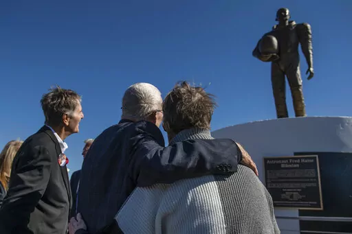 Apollo 13 astronaut Fred Haise Jr., center, hugs sculptor Mary Ott Tremmel Davidson as her statue honoring Haise is unveiled at Biloxi Beach in Biloxi, Miss., Sunday, Feb. 13, 2022. The original ceremony, planned for the 50th anniversary of Apollo 13 in April 2020, was canceled because of COVID-19. Sunday’s event went on despite the death of Haise’s wife, Patt, less than a week before. (Hannah Ruhoff/The Sun Herald via AP)
