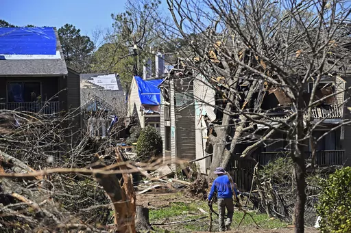 A man drags tree limbs to a pile at the Foxcroft Woods Condominiums, Sunday, April 2, 2023, in Little Rock, Ark. Residents across a wide swath of the U.S. raced to assess the destruction from fierce storms that spawned possibly dozens of tornadoes from the South and the Midwest into the Northeast, killing at least 32 people. (Staci Vandagriff/Arkansas Democrat-Gazette via AP)