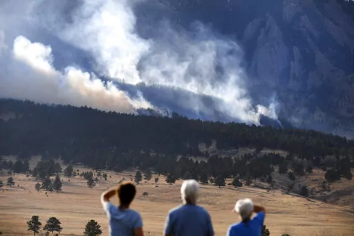 From left to right, Laura Tyson, Tod Smith and Rebecca Caldwell, residents of Eldorado Springs, watch as the NCAR fire burns in the foothills south of the National Center for Atmospheric Research, Saturday, March 26, 2022, in Boulder, Colo. The NCAR fire prompted evacuations in south Boulder and pre-evacuation warning for Eldorado Springs. (Helen H. Richardson/The Denver Post via AP)