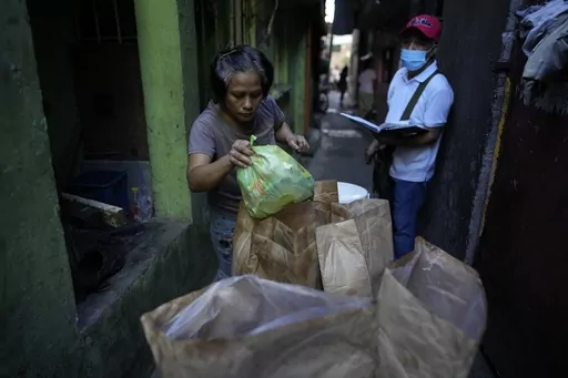 Residents place segregated garbage on a cart along the streets of Malabon, Philippines on Monday Feb. 13, 2023. Food waste emits methane as it breaks down and rots. Waste pickers are helping set up systems to segregate and collect organic waste, and establishing facilities to compost it. (AP Photo/Aaron Favila)