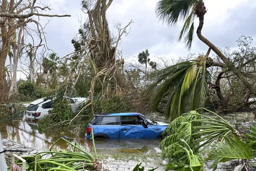 In this undated image from video, damaged vehicles and debris are seen on Sanibel Island, Fla. Chuck Larsen's home was slammed by Hurricane Ian and he spent a harrowing few days on the isolated island before being evacuated over the weekend. (Chuck Larsen/SantivaChronicle.com via AP)