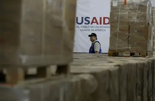 A man walks past boxes of USAID humanitarian aid at a warehouse at the Tienditas International Bridge on the outskirts of Cucuta, Colombia, Feb. 21, 2019, on the border with Venezuela. (AP Photo/Fernando Vergara)