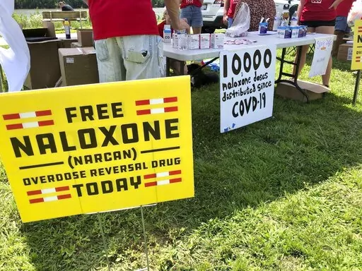 Signs are displayed at a tent during a health event on June 26, 2021, in Charleston, W.Va. The effort to hold drug companies, pharmacies and distributors accountable for their role in the opioid crisis has led to a whirlwind of legal activity around the United States. New legal settlements are being reached practically every week to provide governments money to fight the crisis, and in some cases funds for medicines to reverse overdoses or to help with treatment. (AP Photo/John Raby, File)