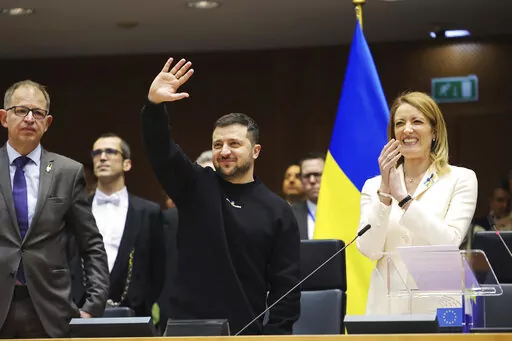 Ukraine's President Volodymyr Zelenskyy, centre, gestures as European Parliament's President Roberta Metsola, right, applauds during an EU summit at the European Parliament in Brussels, Belgium, Thursday, Feb. 9, 2023. On Thursday, Zelenskyy will join EU leaders at a summit in Brussels, which German Chancellor Olaf Scholz described as a "signal of European solidarity and community." (AP Photo/Olivier Matthys)