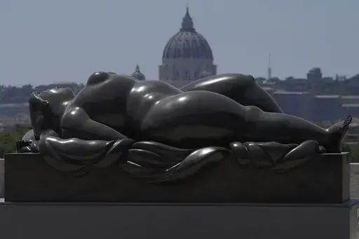 Botero's "Sleeping Venus" sculpture, installed in Rome's Pincio Terrace, Friday, July 19, 2024, appears to be in front of St. Peter's Basilica at The Vatican. Rome's storied streets and piazzas have become a vibrant canvas for Fernando Botero's exuberant sculptures, turning the city into an open-air museum of voluminous forms and daring artistry. (AP Photo/Gregorio Borgia)