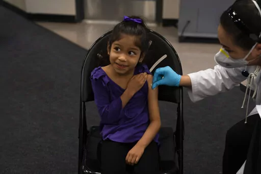 Elsa Estrada, 6, smiles at her mother as pharmacist Sylvia Uong applies an alcohol swab to her arm before administering the Pfizer COVID-19 vaccine at a pediatric vaccine clinic for children ages 5 to 11 set up at Willard Intermediate School in Santa Ana, Calif., Nov. 9, 2021. As of Tuesday, Jan. 11, 2022, just over 17% of children in the U.S. ages 5 to 11 were fully vaccinated, more than two months after shots for them became available. (AP Photo/Jae C. Hong, File)