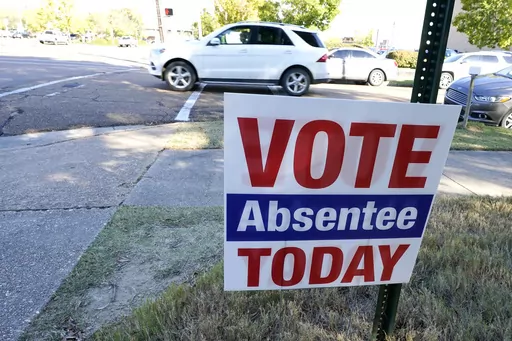 A sign encouraging voters to vote absentee in light of COVID-19 precautions rests on the grounds of the Hinds County Courthouse in Jackson, Miss., Tuesday, Oct. 6, 2020. A federal judge issued an order Tuesday, July 25, 2023, to block a new Mississippi law that would restrict who could help people with absentee voting.(AP Photo/Rogelio V. Solis)