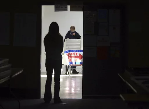 A first-time voter waits in the doorway for a voting booth as another voter completes his ballot at the Boot City Opry near Terre Haute, Ind., Nov. 3, 2020. (Joseph C. Garza/The Tribune-Star via AP, File)