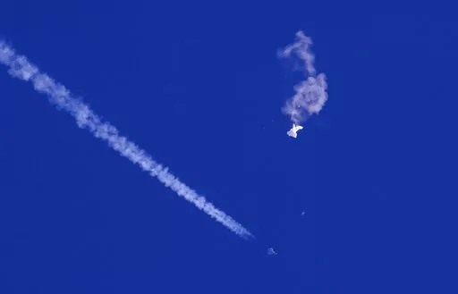A fighter jet flies past the remnants of a large balloon after it was shot down above the Atlantic Ocean, just off the coast of South Carolina near Myrtle Beach, Feb. 4, 2023. The missile fired by a U.S. F-22 ended the days-long flight of what the Biden administration says was a surveillance operation that took the Chinese balloon near U.S. military sites. It was an unprecedented incursion across U.S. territory for recent decades, and raised concerns among Americans about a possible escalation i