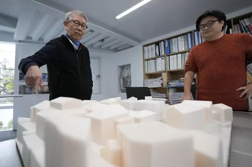 Japan's Riken Yamamoto, left, laureate of Pritzker Architecture Prize, speaks with his staff member near a scale model of a building at his office Wednesday, March 6, 2024, in Yokohama near Tokyo. The Pritzker Architecture Prize has been awarded to Japan’s Riken Yamamoto, who earns the field’s highest honor for what organizers called a long career focused on "multiplying opportunities for people to meet spontaneously, through precise, rational design strategies." (AP Photo/Eugene Hoshiko)