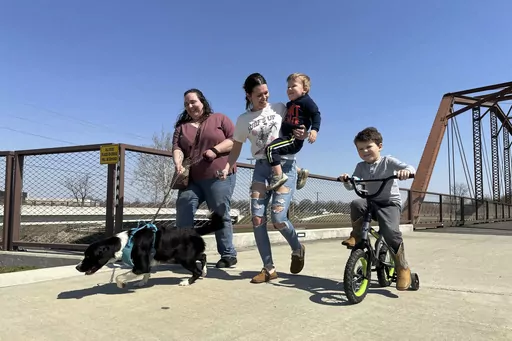 From left; Emerson Howard and dog Dixie enjoy a walk along with Destiny Porter and her children, 2-year old Merrick Mercer and 4-year old Maxton Mercer at the Kitselman bridge connecting the Cardinal and White River Greenway trails in Muncie, Ind., Wednesday, March 13, 2024. The Cardinal Greenways pathway born from eastern Indiana's abandoned railroad tracks will become a central cog in the Great American Rail Trail — a planned 3,700-mile network of uninterrupted trails spanning from Washingto