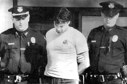 Peter Dushame, 33, of North Andover, Mass., center, is lead out of Nashua District Court in Nashua, N.H. on Oct. 3, 1989, after his arraignment on a negligent homicide charge. Dushame, who was found guilty of manslaughter, earned a master's degree in counseling psychology and changed his name to Peter Stone while in prison, and was released in 2002. In July 2021, he was arrested on charges he sexually assaulted a woman he was counseling in North Conway, N.H. (AP Photo/File)