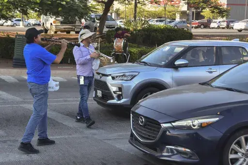 Musicians play for tips from motorists in Culiacan, Sinaloa state, Mexico, Monday, Oct. 14, 2024. (AP Photo)