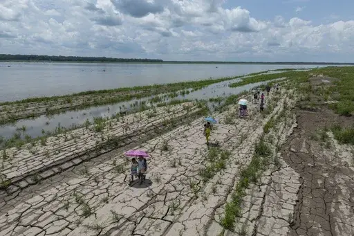 People walk through a part of the Amazon River that shows signs of drought, in Santa Sofia, on the outskirts of Leticia, Colombia, Oct. 20, 2024. (AP Photo/Ivan Valencia, File)