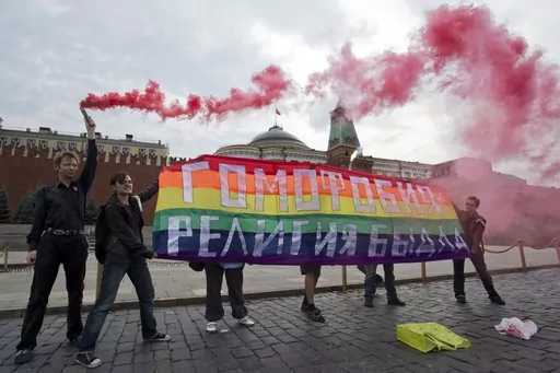 Gay rights activists hold a banner reading "Homophobia - the religion of bullies" during their action in protest at homophobia, on Red Square in Moscow, Russia, on July 14, 2013. Russian lawmakers have approved a toughened version of a bill that outlaws gender transitioning procedures, with added clauses that mandate annulling marriages in which one person has "changed gender" and barring transgender people from becoming foster or adoptive parents. (AP Photo/Evgeny Feldman, File)