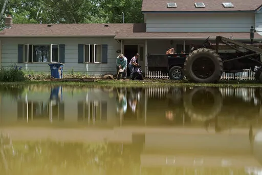 Aileen Rogers, right, and Melody Murter help clean out a friend's house badly damaged by the severe flooding in Fromberg, Mont., Friday, June 17, 2022. (AP Photo/David Goldman)