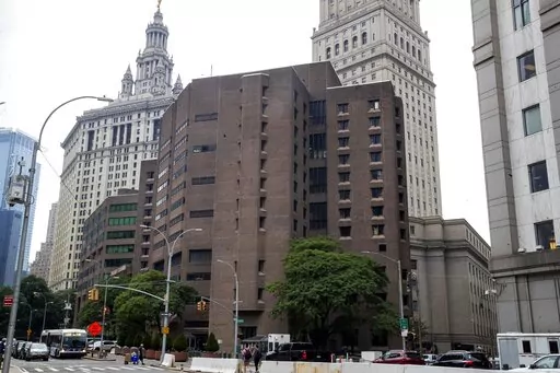 The brown bricked Metropolitan Correctional Center is shown in the foreground with municipal and court facilities in the background, Aug. 13, 2019, in New York. A federal correctional officer was arrested Friday, March 18, 2022, for lying to investigators after a loaded gun was found in an inmate's cell at the federal jail — the same lockup where Jeffrey Epstein killed himself in 2019. (AP Photo/Mary Altaffer, File)