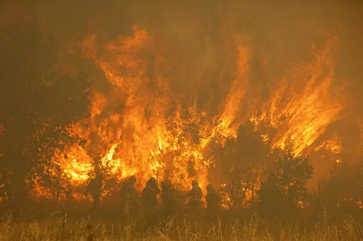 Firefighters work in front of flames during a wildfire in the Sierra de la Culebra in the Zamora Provence on Saturday June 18, 2022. Thousands of hectares of wooded hill land in northwestern Spain have been burnt by a wildfire that forced the evacuation of hundreds of people from nearby villages. Officials said the blaze in the Sierra de Culebra mountain range started Wednesday during a dry electric storm. (Emilio Fraile/Europa Press via AP)