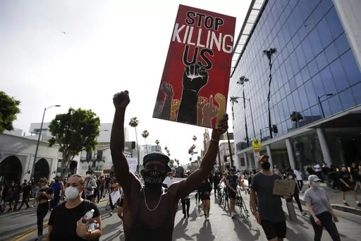 A protester carries a sign in the Hollywood area of Los Angeles on June 1, 2020, during demonstrations after the killing of George Floyd which sparked calls for a racial reckoning to address structural racism that has created longstanding inequities impacting generations of Black Americans. Floyd's murder, along with a series of killings of other Black Americans wrought a heavy emotional and mental toll on Black communities that have already been burdened and traumatized by centuries of oppressi