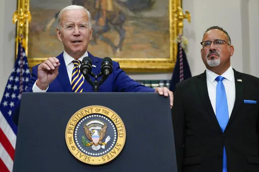 President Joe Biden speaks about student loan debt forgiveness in the Roosevelt Room of the White House, Wednesday, Aug. 24, 2022, in Washington. Education Secretary Miguel Cardona listens at right. (AP Photo/Evan Vucci)