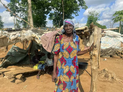 Rifkatu Andruwus, 66, stands in front of her makeshift home, at the Durami camp for the displaced, in Abuja, Nigeria, Friday, June 9, 2023. Hundreds remain homeless in Nigeria's capital of Abuja after losing their shanties to government bulldozers. Authorities say the demolitions seek to rid the city of crime and restore Abuja's master plan, a conceptual layout meant to promote growth of this oil-rich Western African nation. (AP Photo/Chinedu Asadu)