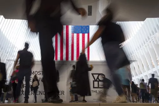 People walk past an American flag inside the Oculus, part of the World Trade Center transportation hub, at the start of a work day in New York, Sept. 11, 2019. American lore is full of tales of a nation built on the foundations of individualism. In reality, loneliness in America can be deadly. In May 2023, the U.S. surgeon general declared it an epidemic, saying that it takes as deadly a toll as smoking. (AP Photo/Wong Maye-E, File)