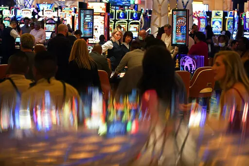 In this June 24, 2021, photo, visitors crowd the casino during the opening night of the Resorts World Las Vegas hotel-casino in Las Vegas. Nevada casinos reported near-record March 2022 house winnings, while the airport in Las Vegas reported passenger traffic almost as heavy as pre-pandemic levels and tourism officials marked another big jump in visitor volume. (AP Photo/John Locher, File)