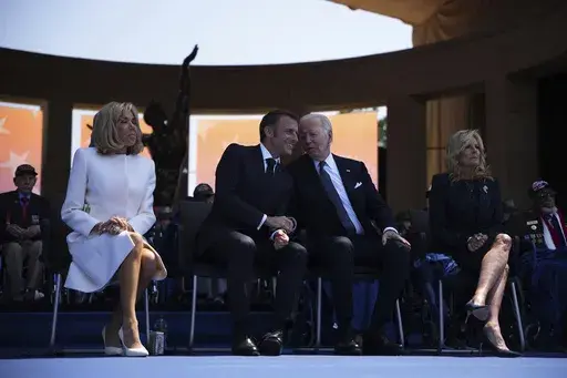 President Joe Biden and First Lady Jill Biden, right, sit on stage with French President Emmanuel Macron, second left, and his wife Brigitte Macron during a commemorative ceremony to mark D-Day 80th anniversary, Thursday, June 6, 2024 at the US cemetery in Colleville-sur-Mer, Normandy. On Friday, June 7, The Associated Press reported on stories circulating online incorrectly claiming Biden was trying to sit in a chair that wasn’t there during a ceremony in Normandy, France, commemorating the 8