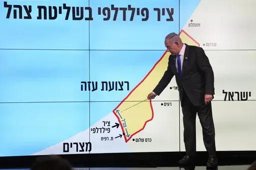 Israeli Prime Minister Benjamin Netanyahu stands before a map of the Gaza Strip, telling viewers that Israel must retain control over the "Philadelphi corridor," a strategic area along the territory's border with Egypt, during a news conference in Jerusalem, Monday, Sept. 2, 2024. The Hebrew on the screen reads, "Philadelphi corridor under Israeli military control." (AP Photo/Ohad Zwigenberg, Pool)