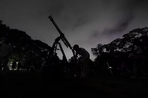 A girl looks at the moon through a telescope in Caracas, Venezuela, on Sunday, May 15, 2022. The best day to spot five planets, Mercury, Jupiter, Venus, Uranus and Mars, lined up in the night sky is Tuesday, March 28, 2023, right after sunset. The five-planet array will be visible from anywhere on Earth, as long as you have clear skies. (AP Photo/Matias Delacroix)