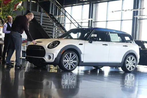 Salesmen examine an unsold 2024 Cooper Clubman S utility vehicle at a Mini dealership May 1, 2024, in Highlands Ranch, Colo. On Friday, May 31, 2024, the Commerce Department issues its report on consumer spending for April. (AP Photo/David Zalubowski, File)
