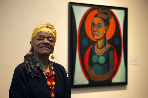 Artist Faith Ringgold poses for a portrait in front of a painted self-portrait during a press preview of her exhibition, "American People, Black Light: Faith Ringgold's Paintings of the 1960s" at the National Museum of Women in the Arts in Washington, June 19, 2013. Ringgold, an award-winning author and artist who broke down barriers for Black female artists and became famous for her richly colored and detailed quilts combining painting, textiles and storytelling, died Friday, April 12, 2024, at