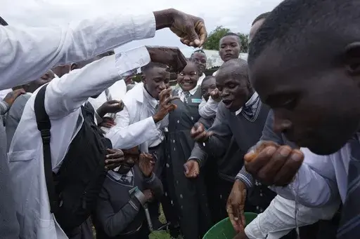 Students, many who are deaf or hard of hearing, from Chileshe Chepela Special School react as Bridget Chanda, center, signs for them during a climate smart technique lesson on drip irrigation outside a garden at the school in Kasama, Zambia, Wednesday, March 6, 2024. Chanda is intent on helping educate Zambia’s deaf community about climate change. As the southern African nation has suffered from more frequent extreme weather, including its current severe drought, it’s prompted the Zambian go