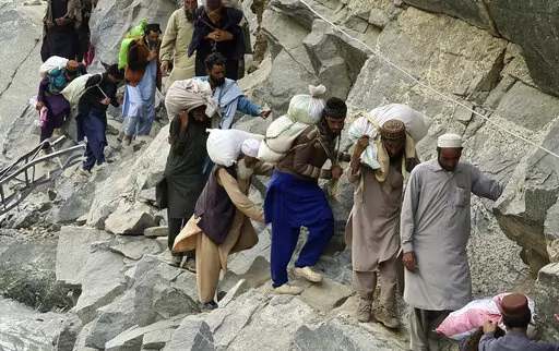 Local residents cross a portion of road destroyed by floodwaters in Kalam Valley in northern Pakistan, Sunday, Sept. 4, 2022. Officials warned Sunday that more flooding was expected as Lake Manchar in southern Pakistan swelled from monsoon rains that began in mid-June and have killed nearly 1,300 people. (AP Photo/Sherin Zada)
