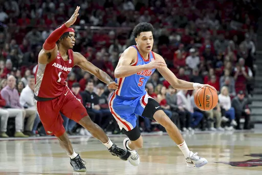 Mississippi guard James White (5) drives past Arkansas guard Ricky Council IV (1) during the first half of an NCAA college basketball game Saturday, Jan. 21, 2023, in Fayetteville, Ark. (AP Photo/Michael Woods)