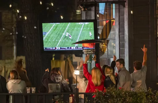 Alabama fans react as they watch television coverage of the College Football Playoff national championship game against Georgia, Monday, Jan. 10, 2022, in Tuscaloosa, Ala.  Brookfield Business Partners is boosting its buyout offer for Nielsen Holdings, Tuesday, March 29, 2022, to about $16 billion after the TV ratings and marketing data company rejected a $9 billion takeover bid.  (AP Photo/Vasha Hunt, File)