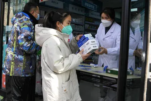 A resident carries away medicine bought at a pharmacy in Beijing, Friday, Dec. 9, 2022. China began implementing a more relaxed version of its strict "zero COVID" policy on Thursday amid steps to restore normal life, but also trepidation over a possible broader outbreak once controls are eased. (AP Photo/Ng Han Guan)