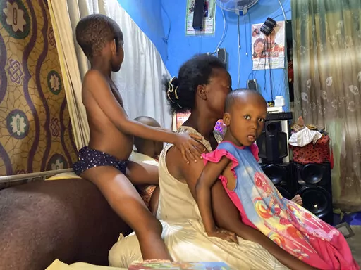 Godgift Inemesit, 28, plays with her children inside her room in Abuja, Nigeria, Monday, Feb. 13, 2023. No one in Godgift Inemesit's family of eight is sure when they will get to eat each day — except for her three kids, two of whom have malaria. She can't pay for the drugs they need or feed the rest of her family regularly. (AP Photo/Chinedu Asadu )