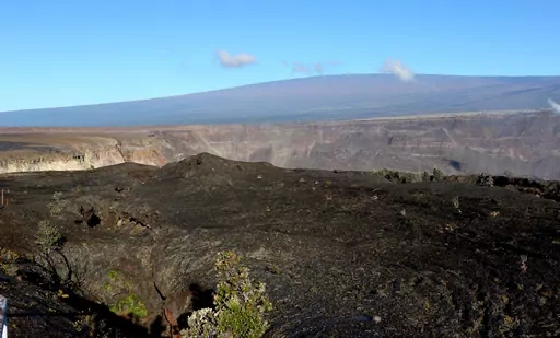Hawaii's Mauna Loa volcano, background, towers over the summit crater of Kilauea volcano in Hawaii Volcanoes National Park on the Big Island on April 25, 2019. A magnitude 5.7 earthquake struck the world's largest active volcano Friday, Feb. 9, 2024, Mauna Loa on the Big Island of Hawaii, knocking items off shelves in nearby towns but not immediately prompting reports of serious damage. (AP Photo/Caleb Jones, File)