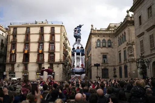 Members of the "Castellers de Poble Sec" complete their human tower during the Saint Eulàlia fesitivities in Barcelona, Spain, Friday, Feb. 11, 2022. After two years of canceled or muted celebrations due to the pandemic, this Mediterranean city went all-out to celebrate the feast, or “fest” in the Catalan language, of its patron. (AP Photo/Joan Mateu Parra)