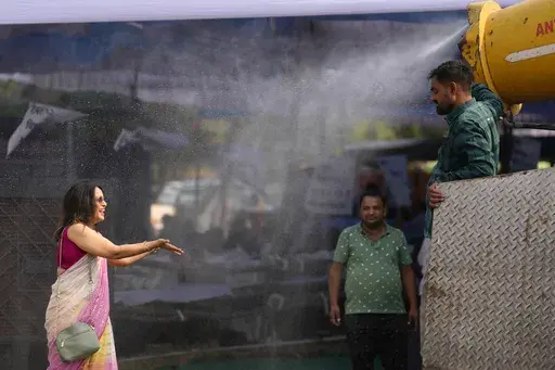 A polling official enjoys a cooling spray of water under intense heat at a distribution venue for Electronic Voting Machines (EVMs) and other election material on the eve of the fifth phase of polling in the six-week-long national election in Lucknow, India, Sunday, May 19, 2024. A top United Nations official says even though climate change makes disasters such as cyclones, floods and droughts more intense, more frequent and striking more places, fewer people are dying from those catastrophes gl