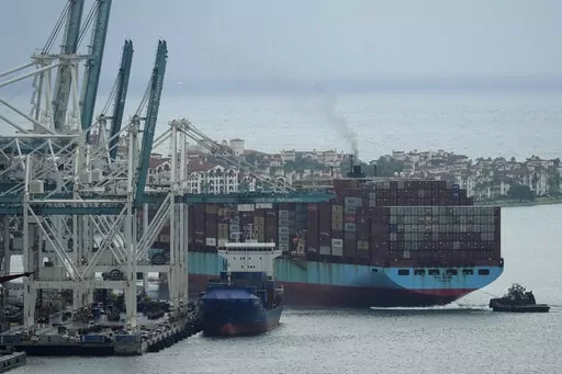 Tugboats guide the Axel Maersk container ship as it arrives into port, Oct. 21, 2021, in Miami. The marine shipping industry is facing new regulations to address carbon pollution. Its trade groups have been seeking exemptions for pollution emitted during voyages on rough seas. (AP Photo/Rebecca Blackwell, File)