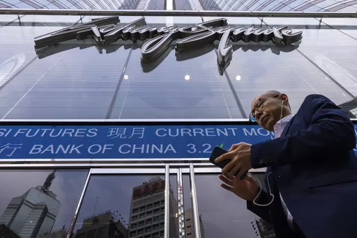 A pedestrian passes by the Hong Kong Stock Exchange electronic screen in Hong Kong, Tuesday, April 18, 2023. Asian shares were trading mixed Tuesday as pessimism about global uncertainties remained even as China reported a better-than-expected economic growth data. (AP Photo/Louise Delmotte)