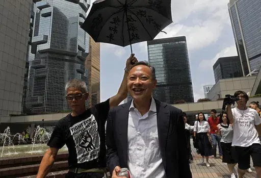 Occupy Central leader Benny Tai, center, is accompanied by a supporter who raises an umbrella as he leaves high court in Hong Kong, on Aug. 15, 2019. (AP Photo/Vincent Yu, File)