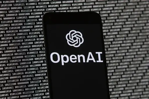 The OpenAI logo appears on a mobile phone in front of a computer screen with random binary data, March 9, 2023, in Boston. (AP Photo/Michael Dwyer, File)