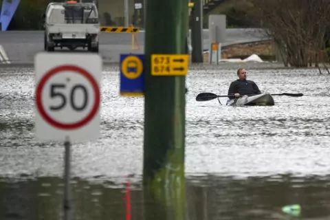 A man paddles his kayak through a flooded street at Windsor on the outskirts of Sydney, Australia, Tuesday, July 5, 2022. Hundreds of homes have been inundated in and around Australia's largest city in a flood emergency that was impacting 50,000 people, officials said Tuesday. (AP Photo/Mark Baker)