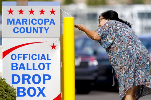 A voter drops off her ballot at a drop box, Nov. 7, 2022, in Mesa, Ariz. Fears of aggressive poll watchers sowing chaos at polling stations or conservative groups trying to intimidate votes didn't materialize on Election Day as many election officials and voting rights experts had feared. Voting proceeded smoothly across most of the U.S., with a few exceptions of scattered disruptions. (AP Photo/Matt York, File)